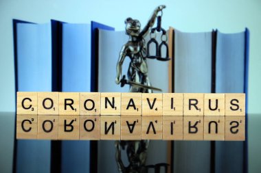 WROCLAW, POLAND - 30 Mart 2020: CORONAVIRUS kelimesi ahşap harflerden yapılmış, ve arka planda hukukun ve adaletin sembolü. Coronavirus (COVID-19) küresel hastalık 2020.