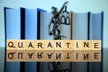 WROCLAW, POLAND - 30 Mart 2020: karantina kelimesi ahşap harflerden yapılmış, ve arka planda hukukun ve adaletin sembolü. Coronavirus (COVID-19) küresel hastalık 2020.