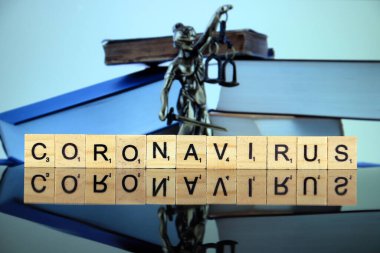 WROCLAW, POLAND - 30 Mart 2020: CORONAVIRUS kelimesi ahşap harflerden yapılmış, ve arka planda hukukun ve adaletin sembolü. Coronavirus (COVID-19) küresel hastalık 2020.