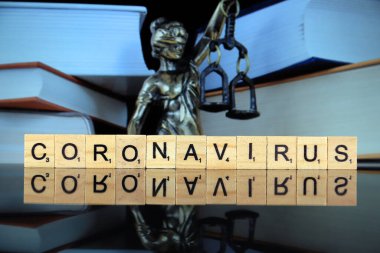 WROCLAW, POLAND - 30 Mart 2020: CORONAVIRUS kelimesi ahşap harflerden yapılmış, ve arka planda hukukun ve adaletin sembolü. Coronavirus (COVID-19) küresel hastalık 2020.