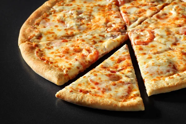 Pizza gesneden close-up met kaas ham en tomaat op een zwarte achtergrond van de stenen — Stockfoto