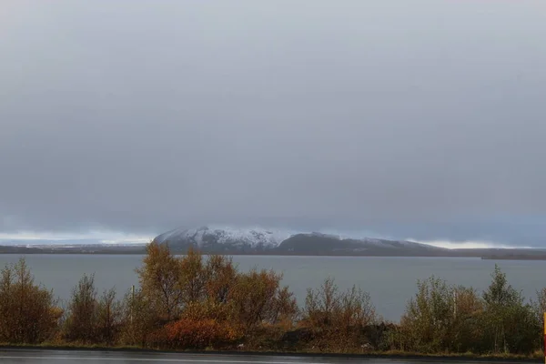 小さな雪に覆われた山の前の道路 — ストック写真