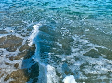 Turkuaz dalgalar sahile çarpıyor.