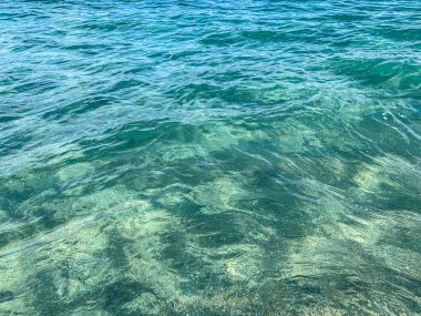 Turkuaz dalgalar sahile çarpıyor.