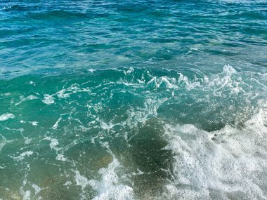 Turkuaz dalgalar sahile çarpıyor.