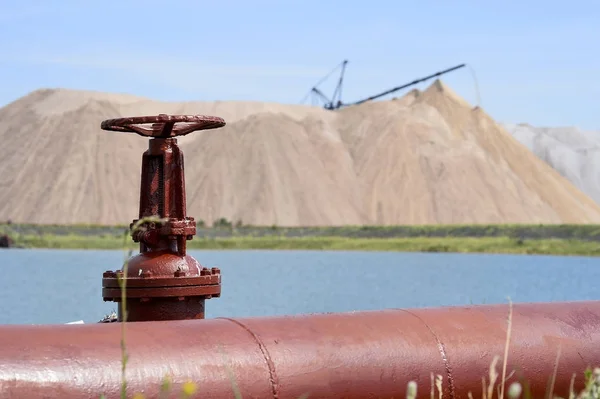 A válvula do gasoduto contra o fundo de uma mina de sal e lago artificial — Fotografia de Stock