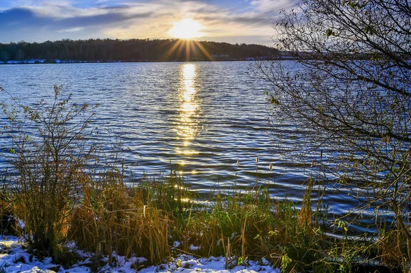 De ondergaande zon op een besneeuwde meer in de late herfst — Stockfoto