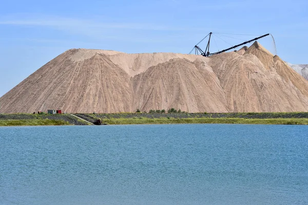 Salt-gruvan i form av en kulle med transportband stenar. I förgrunden är en konstgjord damm — Stockfoto