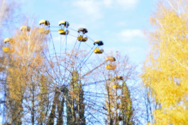 Autumn Park, Ferris roue la vue du bas, les arbres au premier plan avec des feuilles jaunes. Flou. Photographie lentille souple — Photo