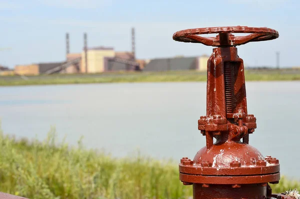 La vanne du pipeline sur fond d'usine et d'un lac artificiel — Photo