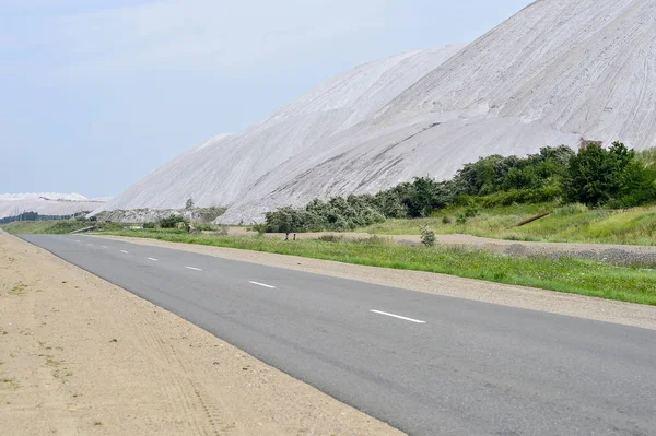 Asphalt road on the edge of the dumps of the mines of Belarus, the city of Soligorsk — Stock Photo, Image