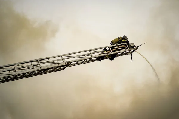 A firefighter puts out a burning building with height extension ladders Stock Photo