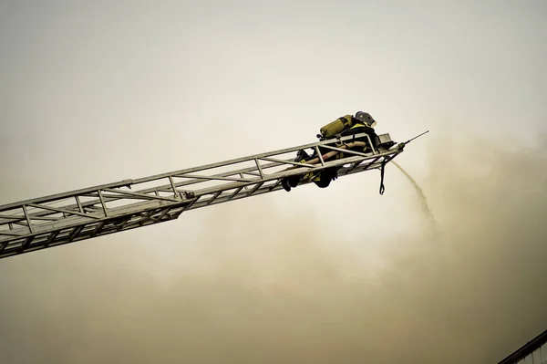 A firefighter puts out a burning building with height extension ladders Royalty Free Stock Images