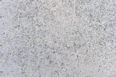 Gray concrete wall interspersed with small stones of natural rubble. Background