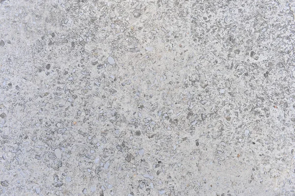 Szara betonowa ściana przeplatana małymi kamieniami naturalnego gruzu. Kontekst — Zdjęcie stockowe