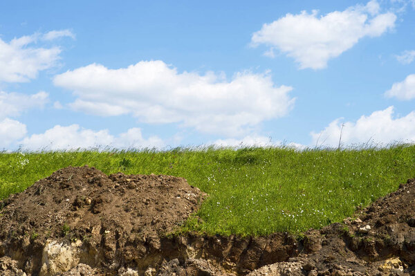 Раскопанная земля начала строительство дороги против голубого неба с облаками
