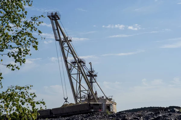 Uma escavadora enorme carrega rocha do trem descarregado da mina. O conceito de mineração e problemas ambientais . — Fotografia de Stock