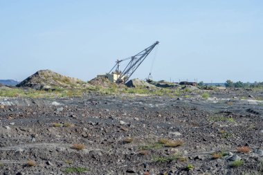 Büyük bir kazıcı, dolu olmayan trenden kaya taşır.