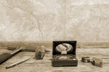 Tools geologist laid out on a wooden table on the background of a topographic map. Background. Toning clipart