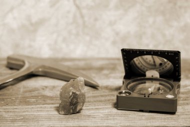 Bir jeologun çekici, bir pusula ve demir cevheri ile karıştırılmış bir mineral ahşap bir masanın üzerine serilmiştir..