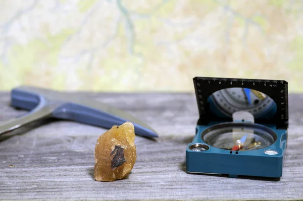 Um martelo geólogos, uma bússola, e um mineral intercalado com minério de ferro são colocados em uma mesa de madeira . — Fotografia de Stock