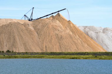 Tuz madeni bir tepe ile konveyör şeklinde kayalar. Yapay bir göl ön planda olduğunu