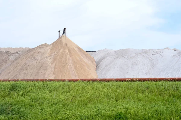 View of the salt mine and an artificial mound with green grass in the foreground — Stock Photo, Image