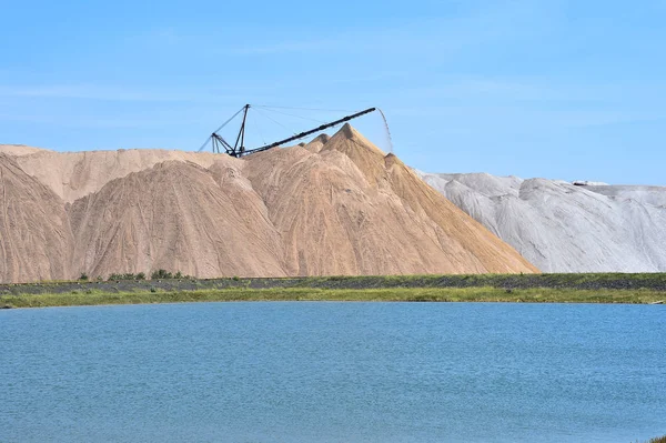 Das Salzbergwerk in Form eines Hügels mit Fördergestein. Im Vordergrund steht ein künstlicher Teich — Stockfoto