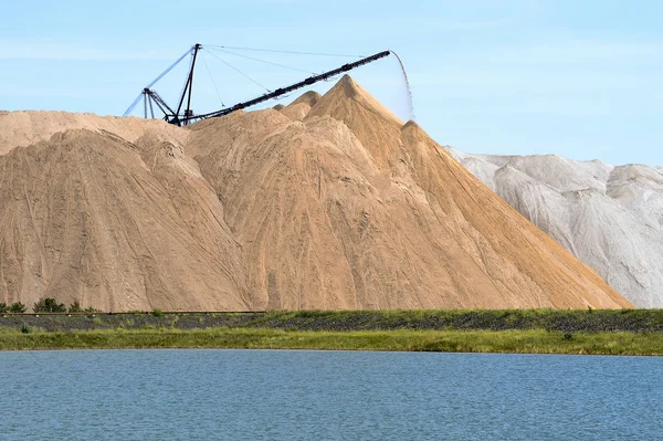 La mina de sal en forma de colina con rocas transportadoras. El primer plano es un estanque artificial —  Fotos de Stock
