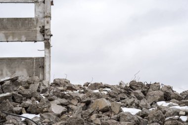 Bulutlu bir gökyüzüne karşı çıkıntılı büyük gri beton parçaları yığını..