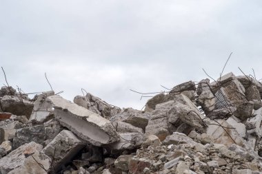 Bulutlu bir gökyüzüne karşı çıkıntılı büyük gri beton parçaları yığını..