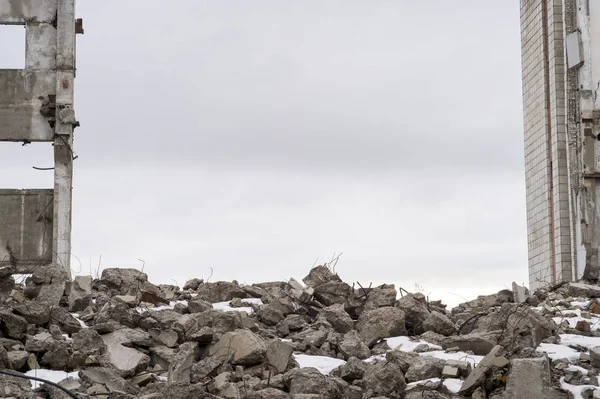 Bulutlu bir gökyüzüne karşı çıkıntılı büyük gri beton parçaları yığını..