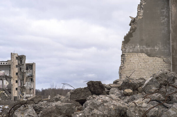 Куча больших серых бетонных фрагментов с выступающей арматурой против облачного неба
.