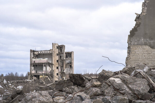 Куча больших серых бетонных фрагментов с выступающей арматурой против облачного неба
.