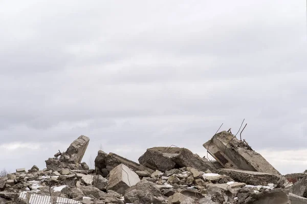 Bulutlu bir gökyüzüne karşı çıkıntılı büyük gri beton parçaları yığını..