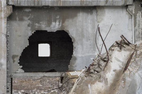 Nitidez em uma parede quebrada. Restos da destruição de um grande edifício de concreto com um buraco na parede . — Fotografia de Stock