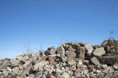 Mavi bulutlu gökyüzüne karşı çıkıntılı büyük gri beton parçaları yığını. Arkaplan.