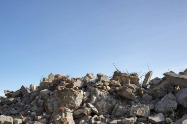 Mavi bulutlu gökyüzüne karşı çıkıntılı büyük gri beton parçaları yığını. Arkaplan.