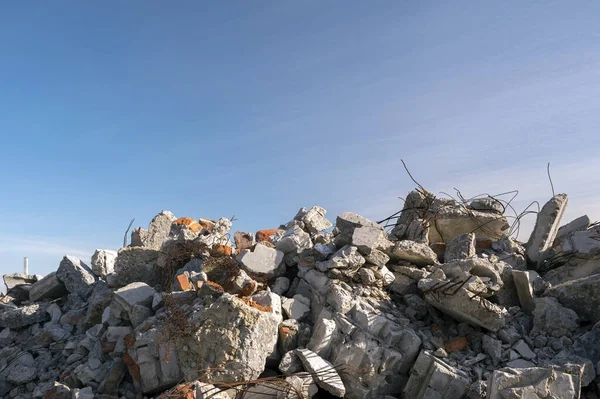 Mavi bulutlu gökyüzüne karşı çıkıntılı büyük gri beton parçaları yığını. Arkaplan.