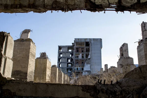 Vista através de uma lacuna na parede de concreto com vergalhões salientes sobre os restos de pilhas de concreto da Fundação . — Fotografia de Stock