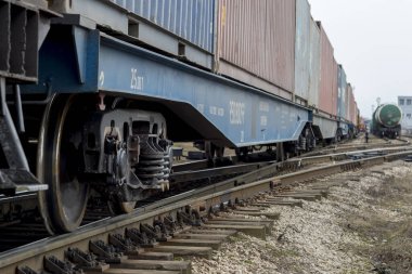 Bir yük treninin vagonları, uzaktan farklı bir bileşime sahip tanklarla uzaklığa doğru uzanıyor. Arkaplan