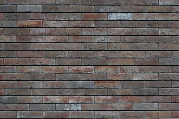 Una pared de ladrillo marrón con una superficie rugosa decorada. Contexto — Foto de Stock