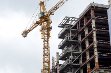 Bulutlu gökyüzüne karşı yüksek binaların iskeletinin inşası. Arkaplan