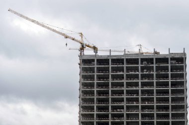 Bulutlu gökyüzüne karşı yüksek binaların iskeletinin inşası. Arkaplan.