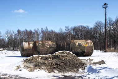 Zeminin yüzeyinde karla kaplı iki büyük metal tank var. Arkaplan.