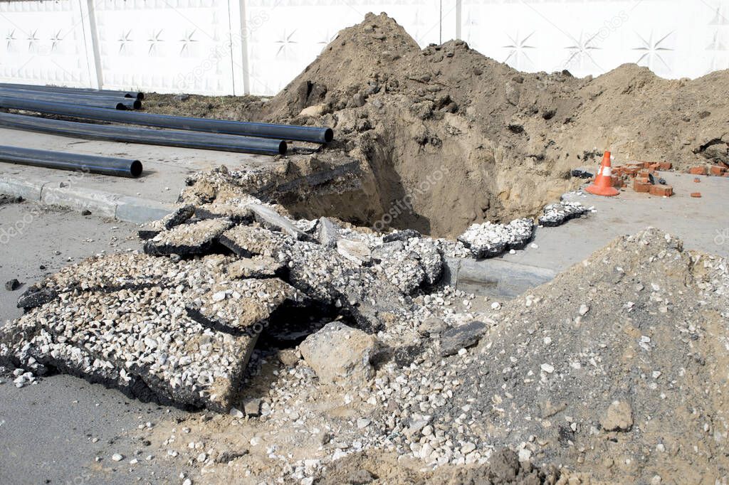 Laying a cold water sewer pipeline in the city asphalt. Background.