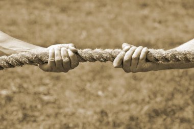 İki adamın eli ipi kendi yönüne çeker. Tartışma, çatışma ve güç kavramı. Tonlama