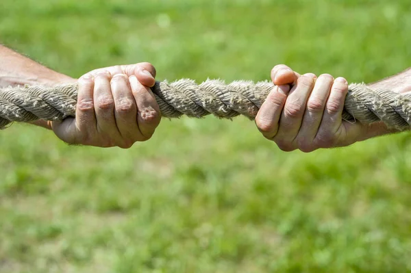 Two mens hands pull the rope each in his own direction. The concept of dispute, conflict and force