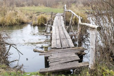Sonbaharda köyde küçük bir nehrin üzerindeki tahta köprü. Geçmişi. Ulaşılması zor yerlerde köy hayatının yolu.