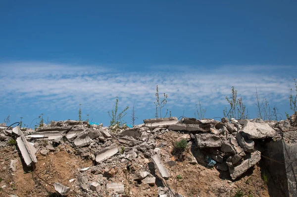 Uma pilha de detritos de concreto cinzento contra um céu azul texturizado com nuvens brancas de penas. Contexto — Fotografia de Stock